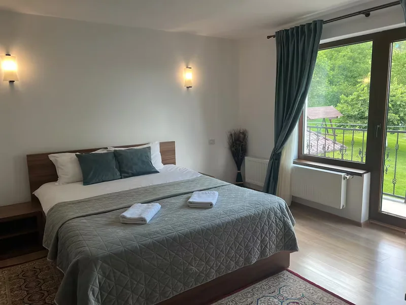 Dormitor cu pat dublu și ușă deschisă spre balcon
